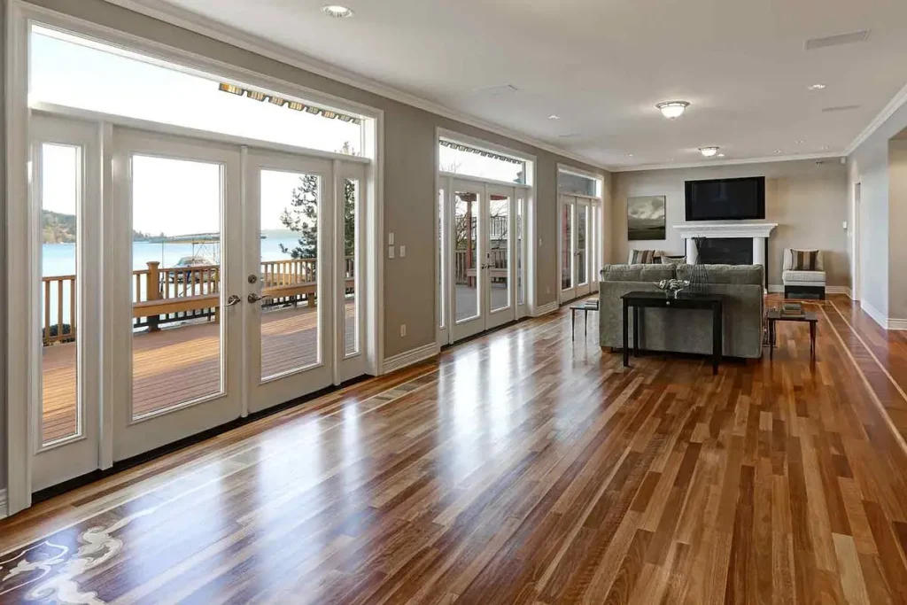 Elegant hardwood floor refinishing in Latham, NY, showcasing a bright, open living space with lakefront views and a smooth, polished finish that enhances natural light.